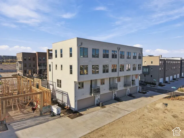 Three-story multi-unit structure featuring a smooth stucco exterior, expansive windows, multiple private recessed balconies, and integrated multi-car garages