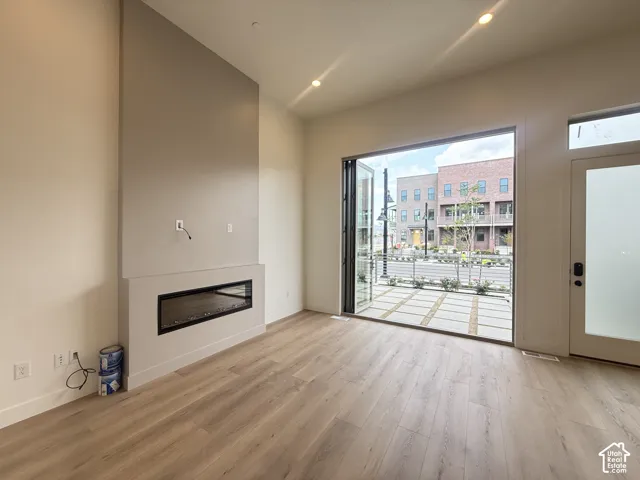 Spacious interior featuring wood-finish flooring, high ceilings with recessed lighting, and a linear electric fireplace