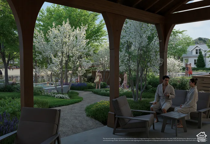 Covered outdoor patio with exposed wood beams, concrete flooring, and surrounding manicured landscaping