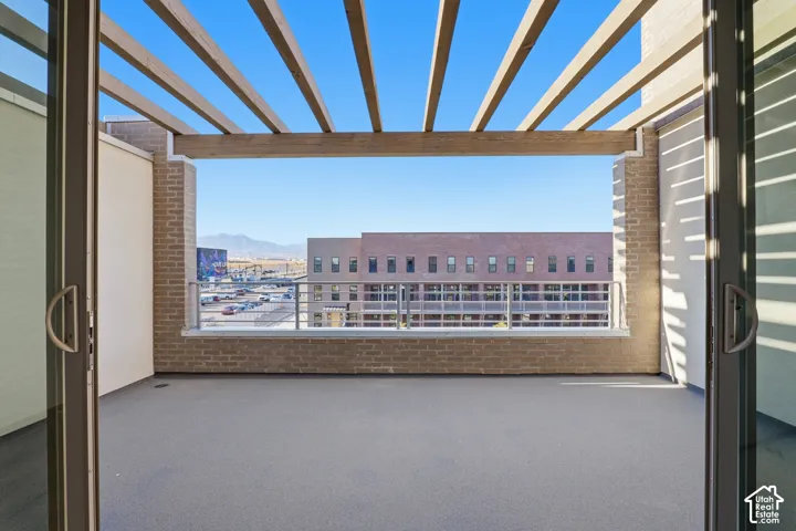 Private balcony featuring a wood-beam pergola, brick masonry walls, and a metal railing