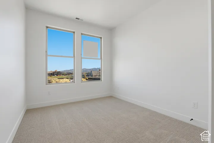 Interior room featuring neutral wall-to-wall carpeting, crisp white walls, and dual-pane windows offering a mountain backdrop