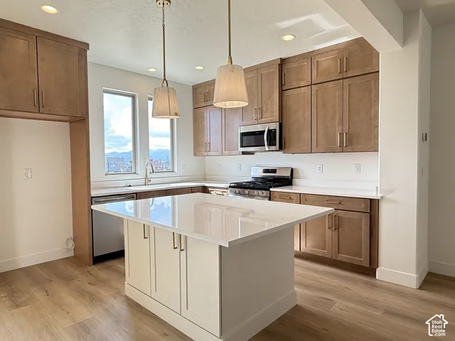 Kitchen featuring a central island, wood-finish flooring, recessed lighting, and pendant fixtures