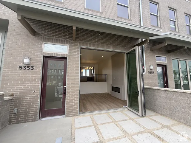 Patio entrance featuring accordion-style glass doors, light brick facade, and concrete pavers