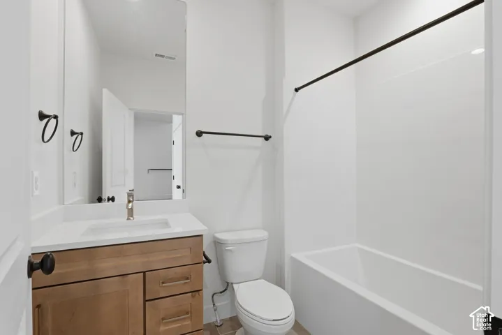 Bathroom featuring a wood-finish vanity with a white countertop, an undermount sink, a tall wall-to-wall mirror, and matte black hardware