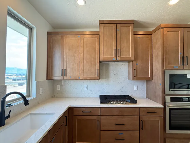 Kitchen featuring light wood cabinetry with dark hardware, a white undermount sink, and a black gooseneck faucet
