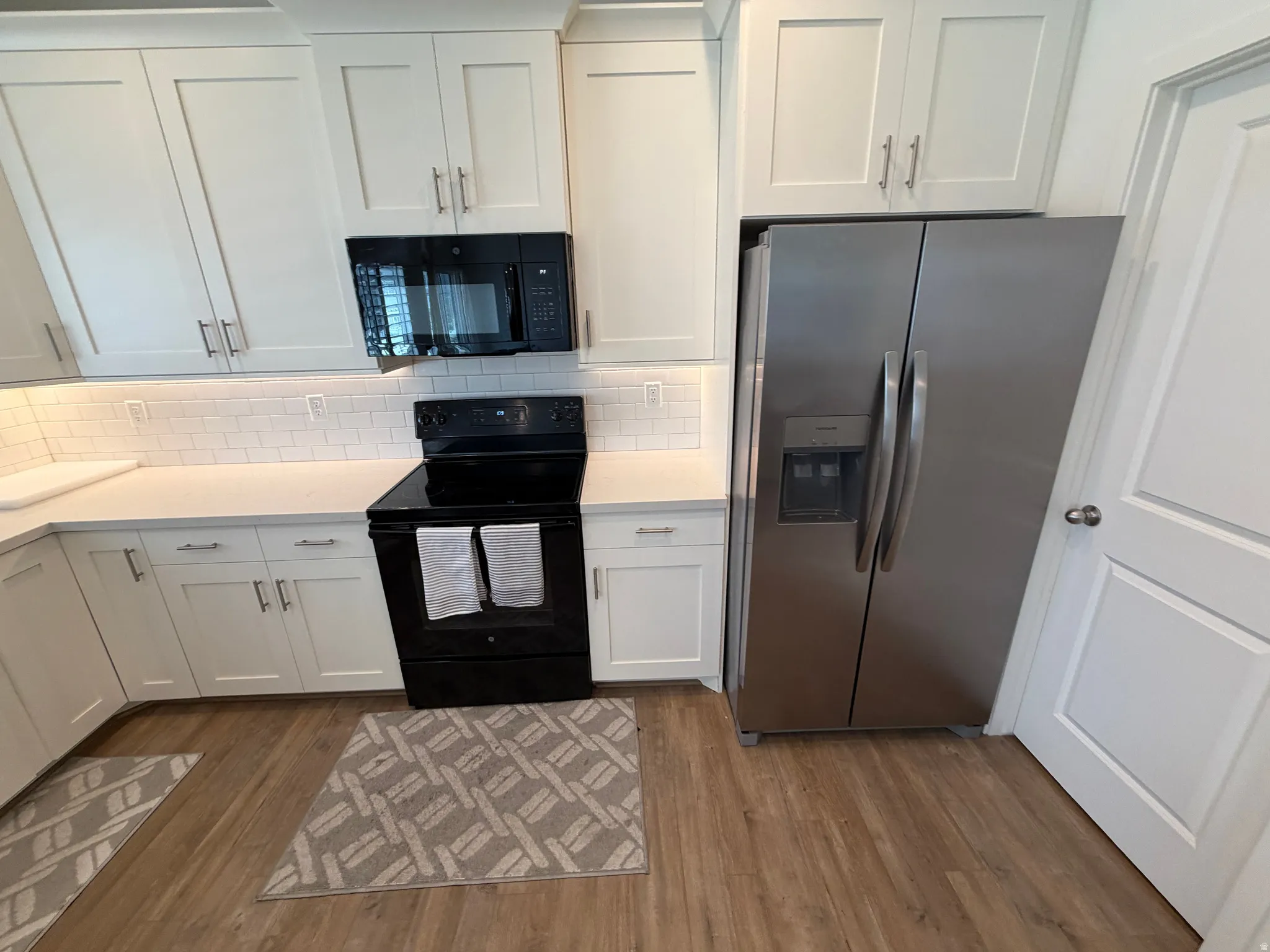 Contemporary kitchen featuring white shaker cabinetry, quartz countertops, and a white subway tile backsplash