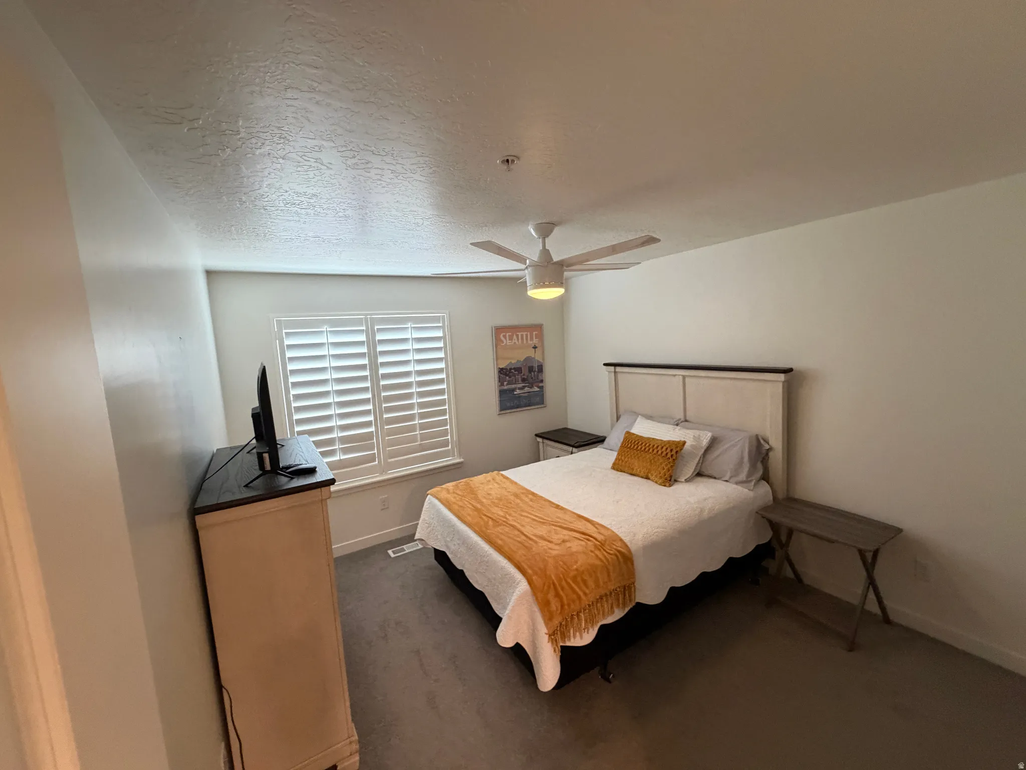 Bedroom featuring a ceiling fan with integrated lighting, plantation shutters, and carpet flooring