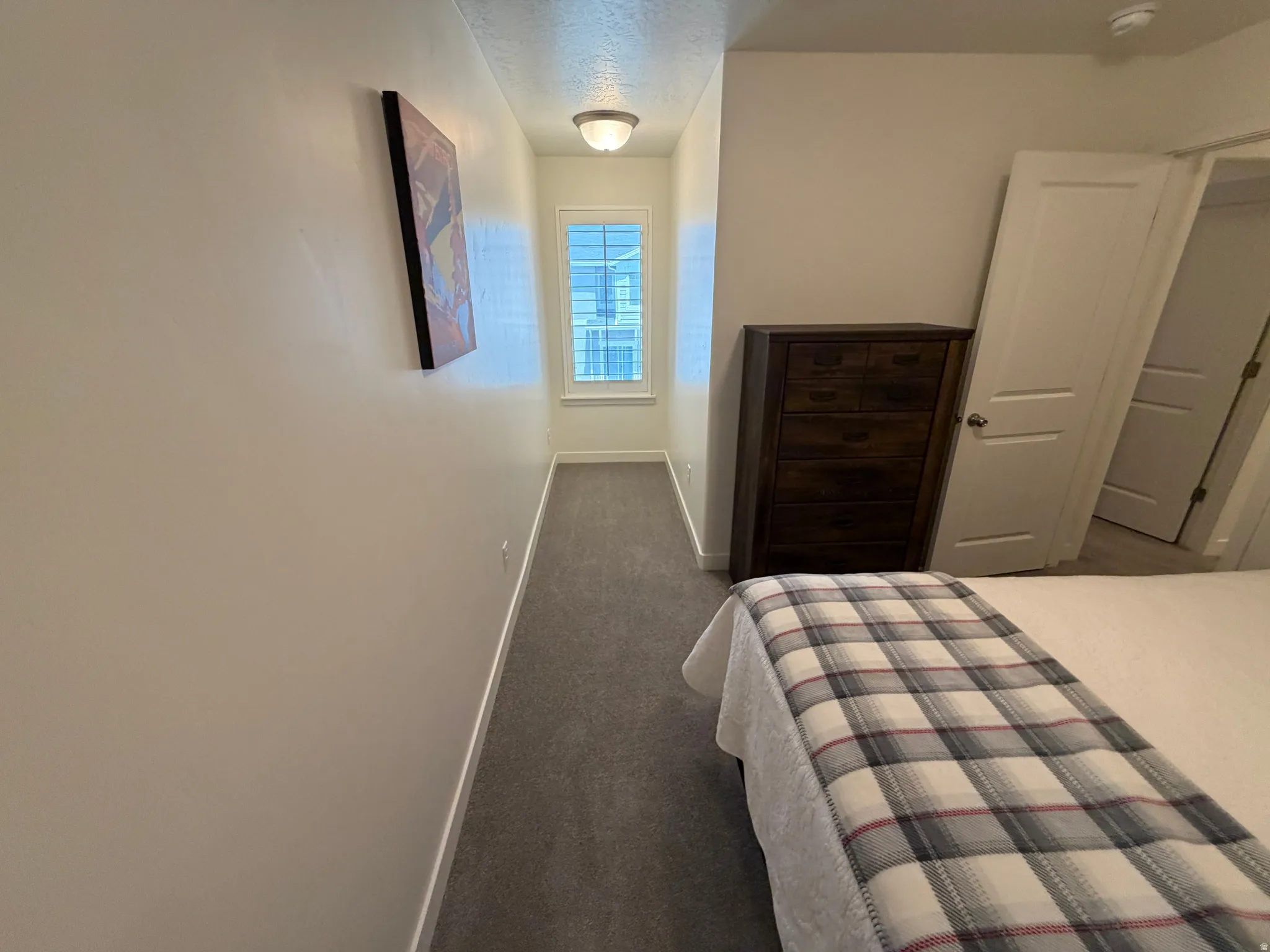 Bedroom featuring neutral wall paint, gray carpet flooring, a single window with blinds, and a flush-mount ceiling light fixture