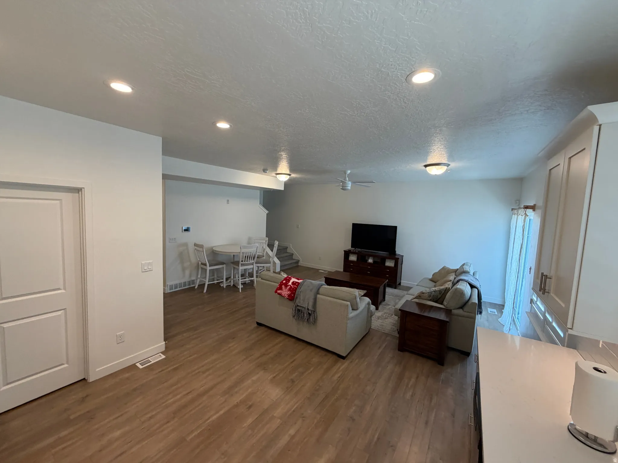 Spacious open-concept living area featuring wood-finish flooring, recessed lighting, and a neutral color palette