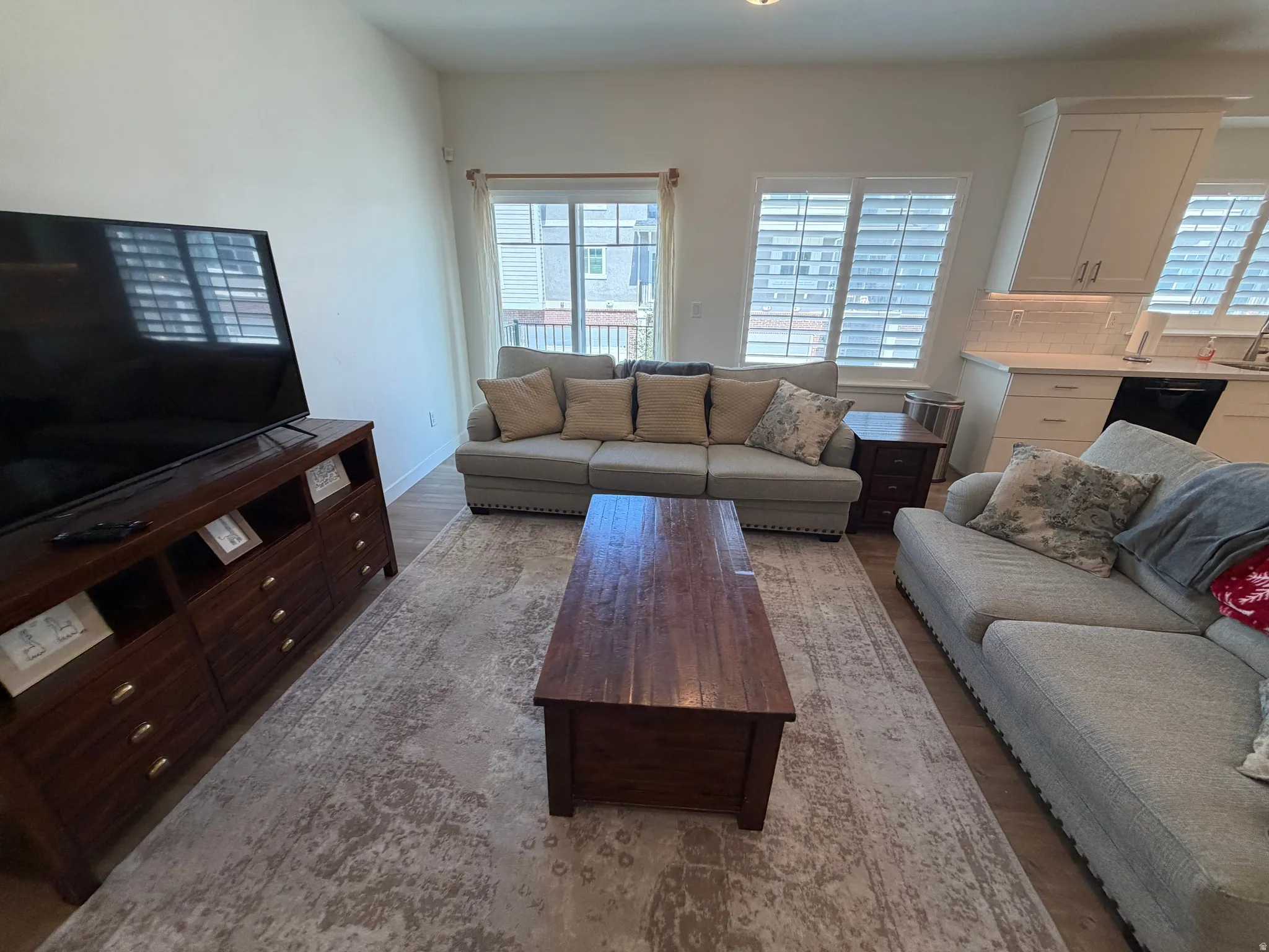 Open-concept living area featuring wood-finish flooring, recessed lighting, and white plantation shutters