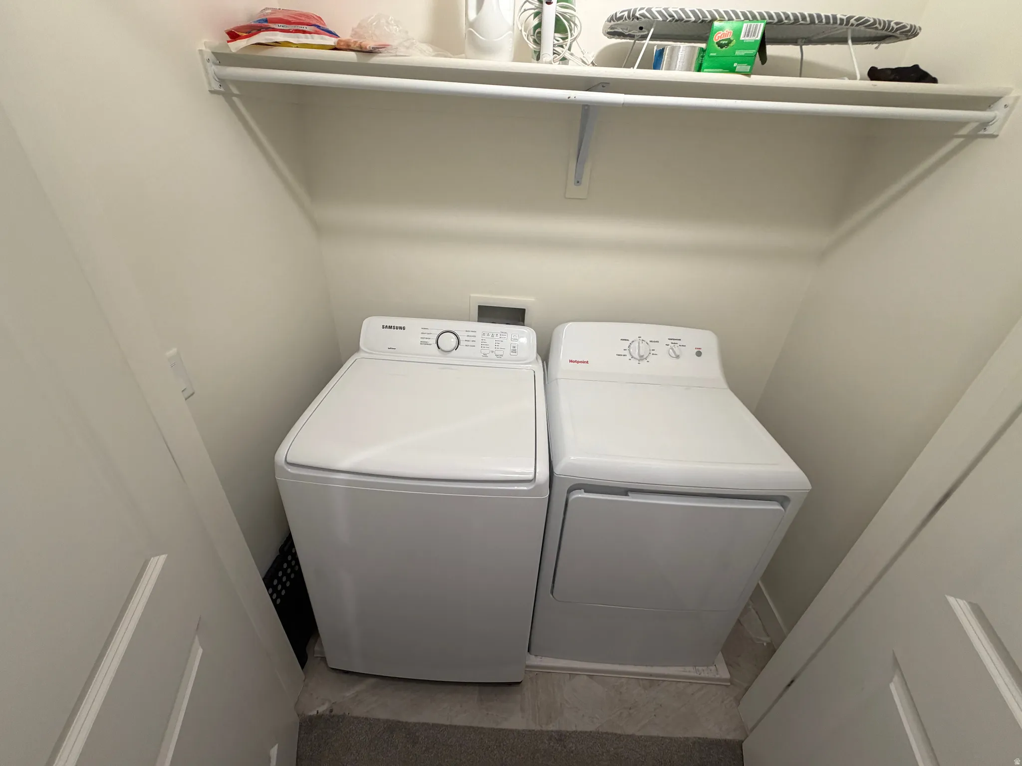Dedicated laundry area featuring a washer and dryer set, overhead shelving, and a built-in hanging rod