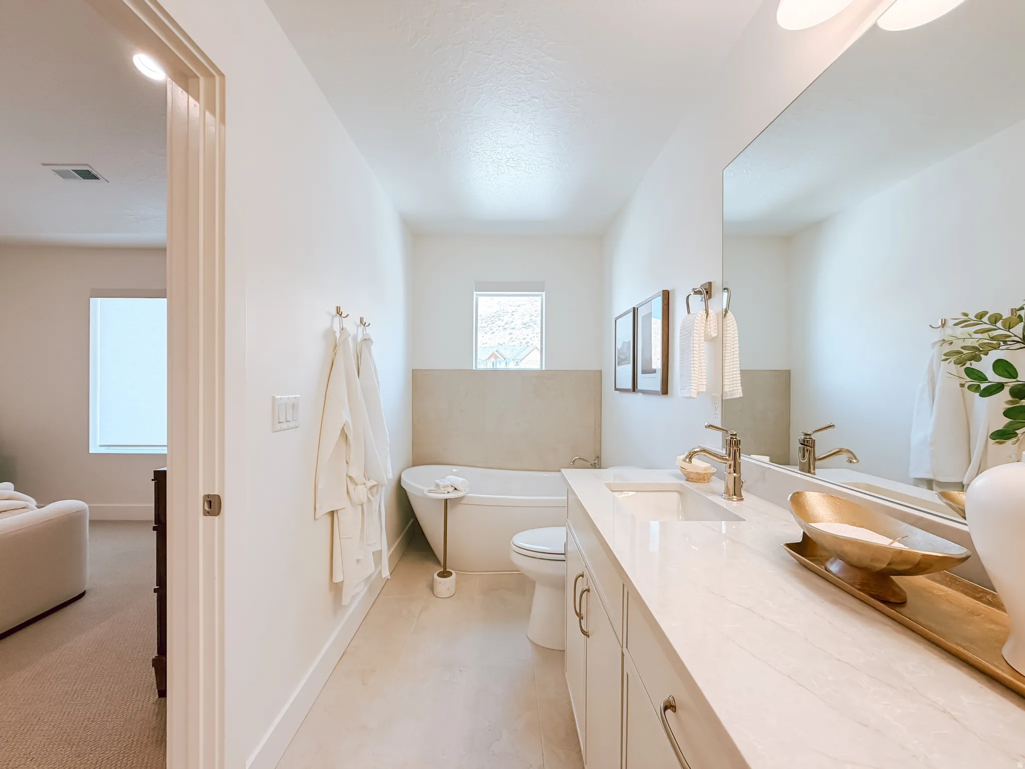 Bright bathroom featuring a freestanding tub, a vanity with dual undermount sinks, and a large wall-mounted mirror