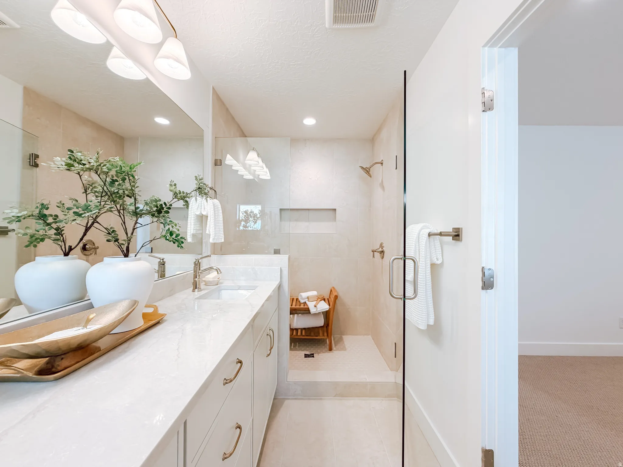 Bathroom featuring a dual vanity with a light-toned countertop, under-mount sinks, and brass-finish hardware