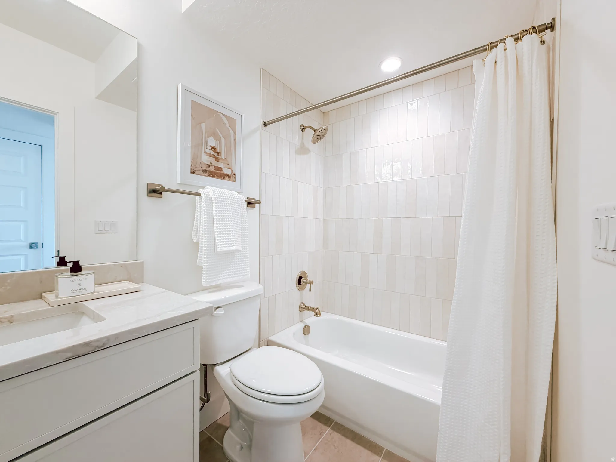 Contemporary bathroom featuring a white vanity with an integrated sink, a large frameless mirror, and a full-size bathtub