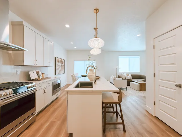 Contemporary kitchen featuring light wood-finish flooring and a central island with integrated sink