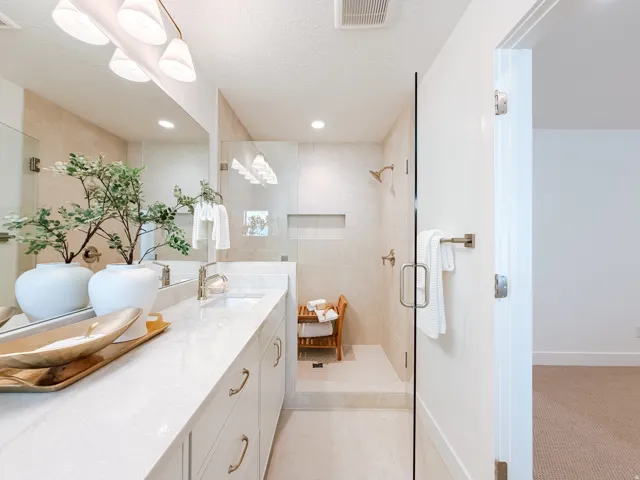 Bathroom featuring a dual vanity with a light-toned countertop, under-mount sinks, and brass-finish hardware