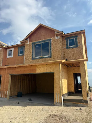 New construction framing featuring a prominent two-car garage opening, multiple window openings with installed window units, and a covered entry