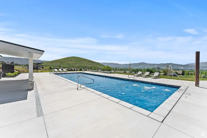 Rectangular swimming pool with water features surrounded by a large concrete deck