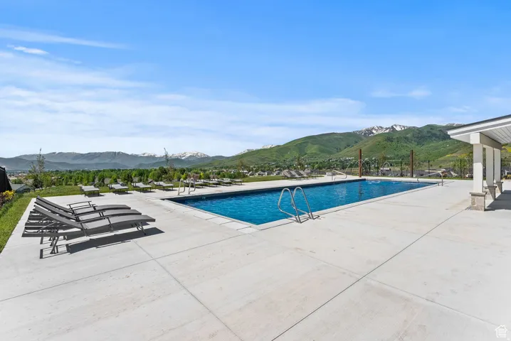 Outdoor swimming pool with concrete decking, surrounded by distant mountains