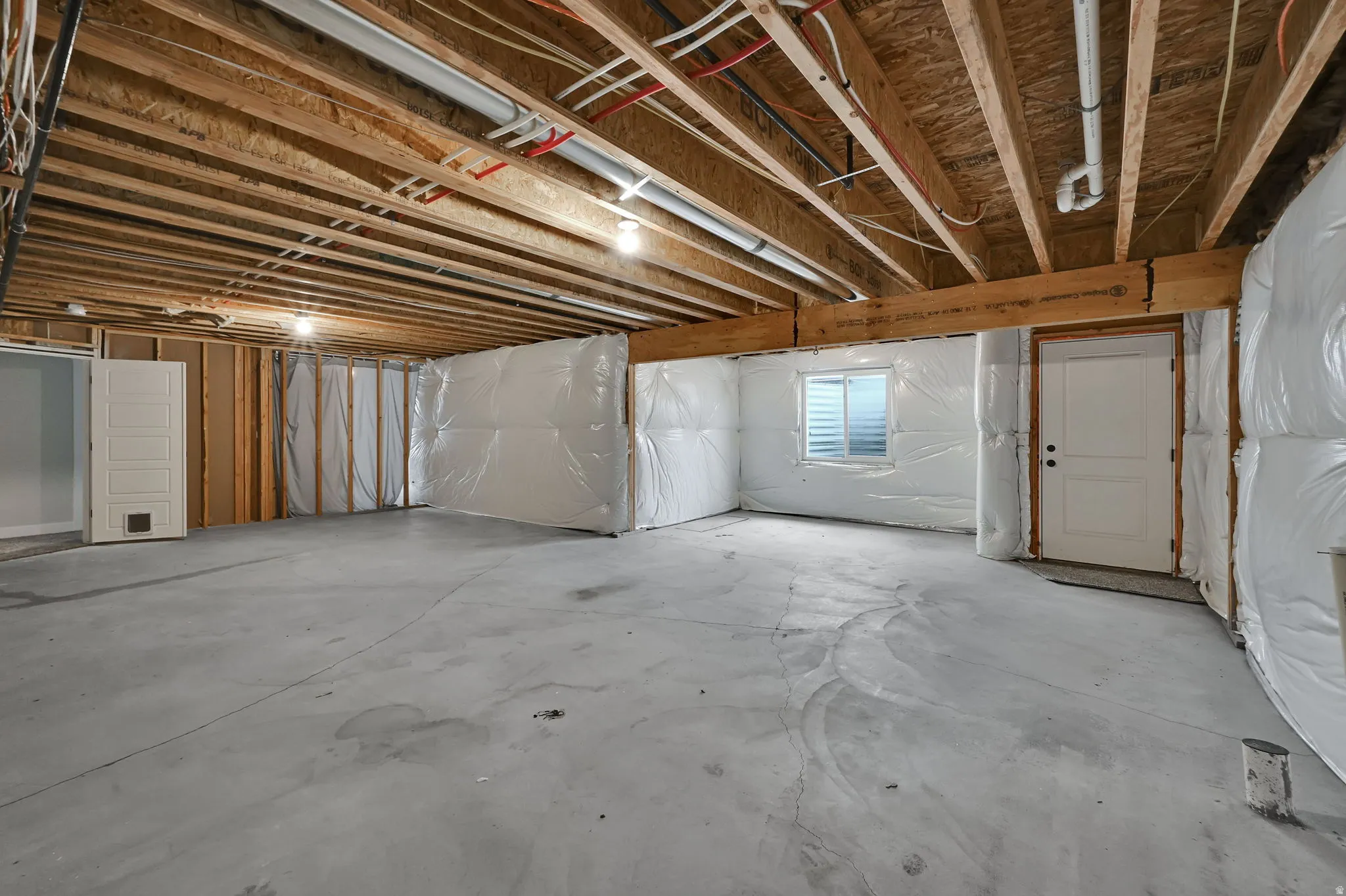 Unfinished basement with exposed ceiling joists and concrete flooring