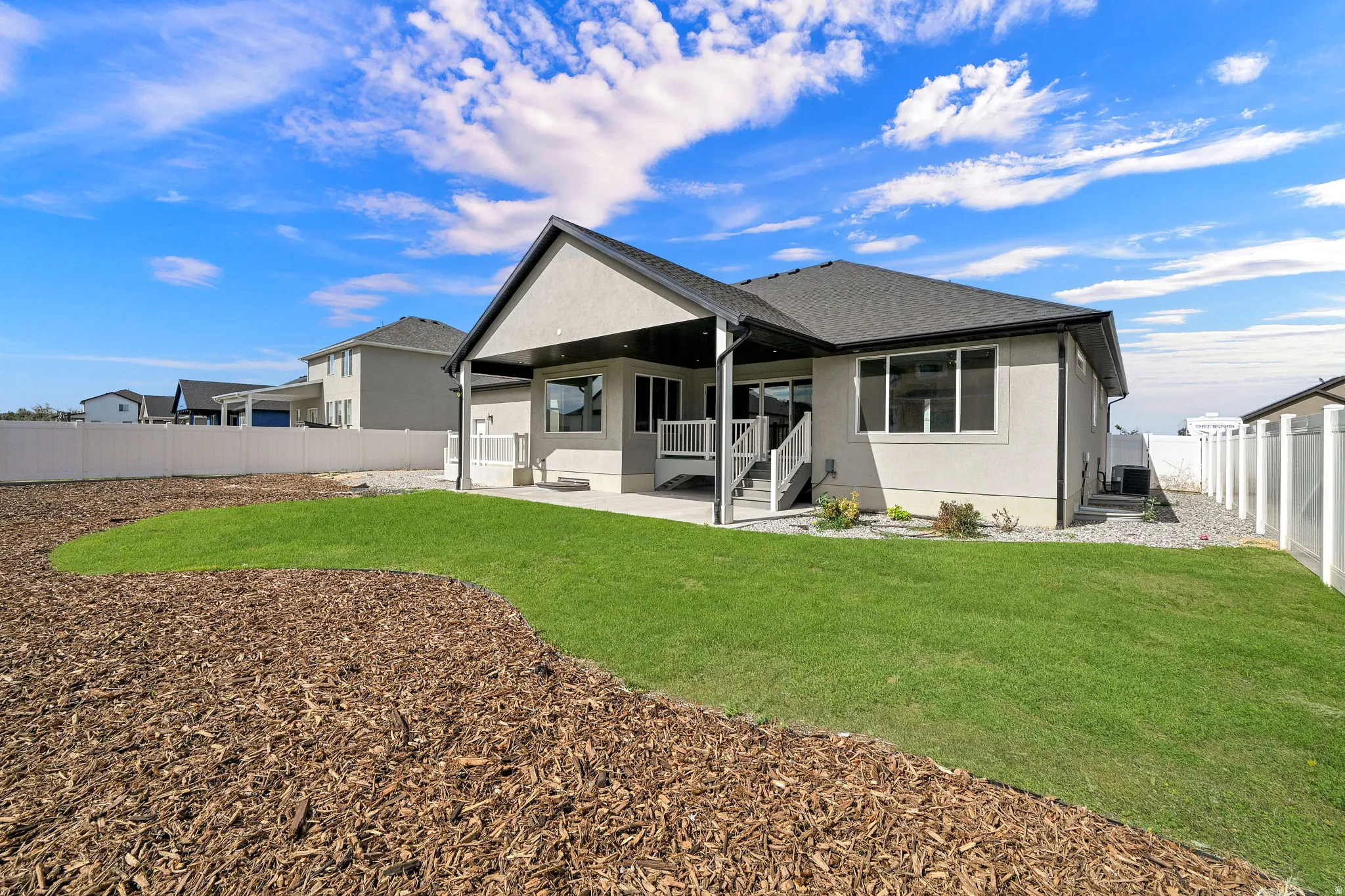 Expansive backyard featuring a manicured lawn, a large covered patio, and a privacy fence