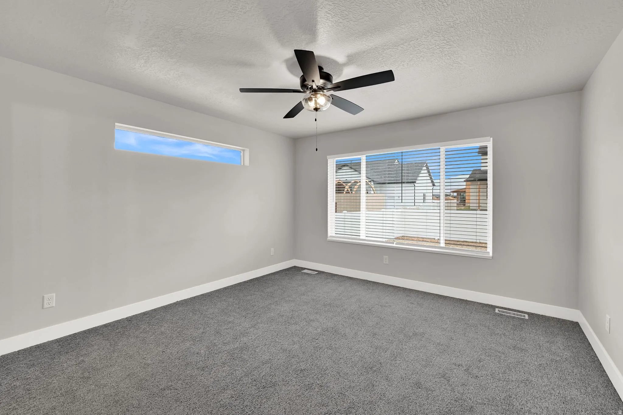 Carpeted flooring, ceiling fan, large window with blinds, and high transom window