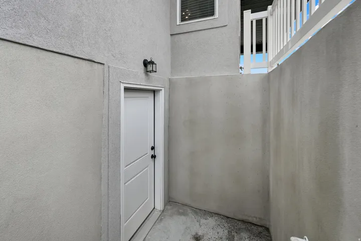 White paneled door, black lantern-style wall sconce, and textured exterior finish