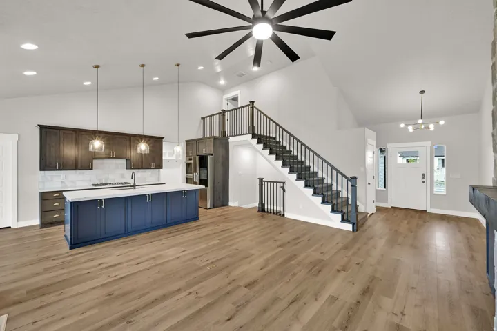 Vaulted ceilings, wood-finish flooring, and a modern kitchen featuring a blue island with a white countertop