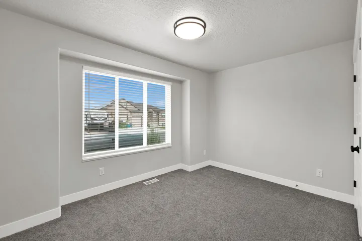 Neutral gray wall paint, window with blinds, gray carpet flooring, white trim, and a flush-mount ceiling light fixture