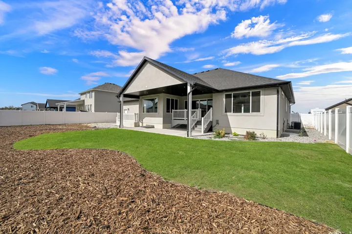 Expansive backyard featuring a manicured lawn, a large covered patio, and a privacy fence
