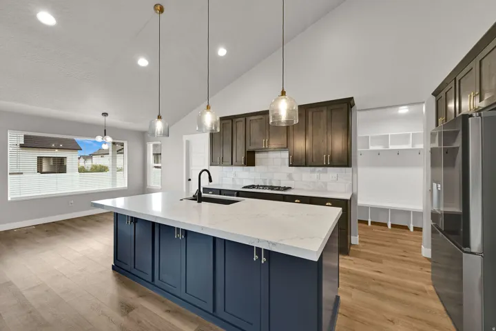 Vaulted ceiling with recessed lighting, large kitchen island with a light-toned countertop, dark wood-finish cabinetry, subway tile backsplash, and wood-finish flooring