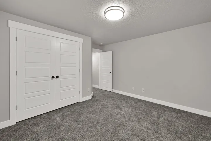 Recessed lighting, light gray wall paint, white trim, gray carpet, and white paneled doors with black hardware