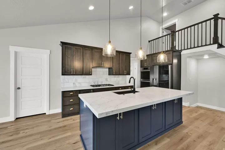 Kitchen featuring vaulted ceilings, wood-finish flooring, dark wood cabinetry, a white tile backsplash, and a large island with a light-colored countertop