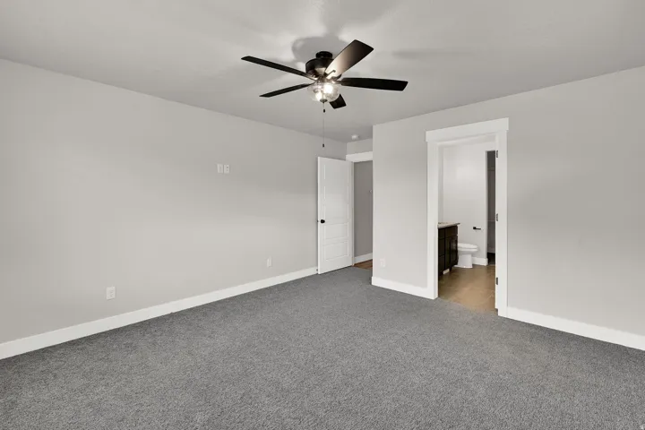 Spacious room featuring neutral wall paint, gray carpeting, and a ceiling fan with integrated lighting