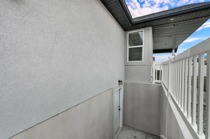 Recessed basement entry featuring a white door, exterior sconce, and textured exterior siding