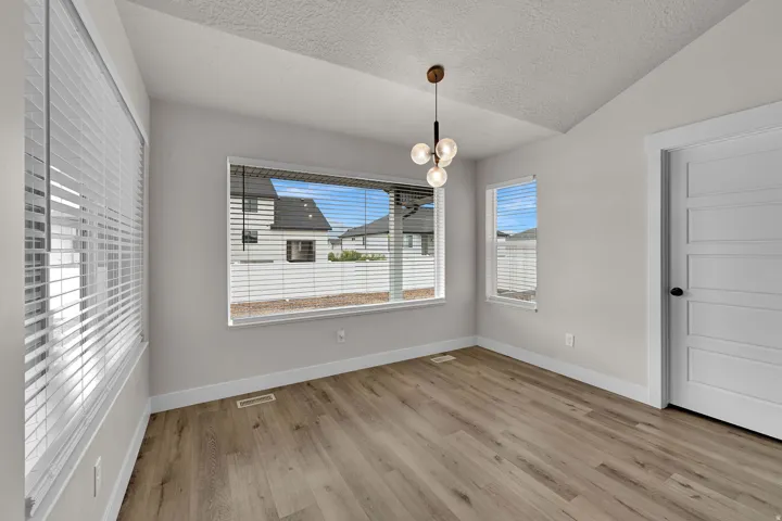 Vaulted ceiling with a modern spherical chandelier, wood-finish flooring, and multiple windows with blinds