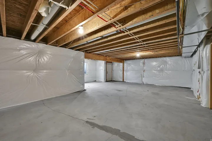 Unfinished basement with exposed ceiling joists and concrete flooring