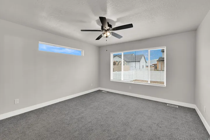 Carpeted flooring, ceiling fan, large window with blinds, and high transom window