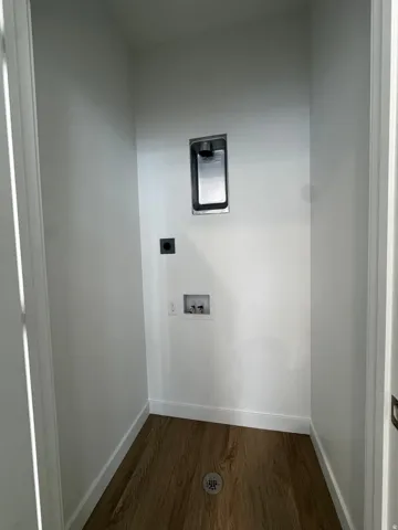 Dedicated utility space featuring wood-finish flooring and a central floor drain