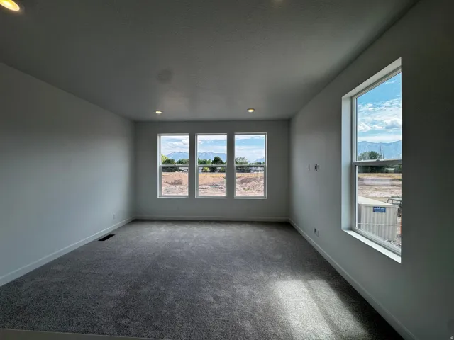 Bright room with multiple windows, recessed ceiling lighting, textured carpeting, and white baseboards