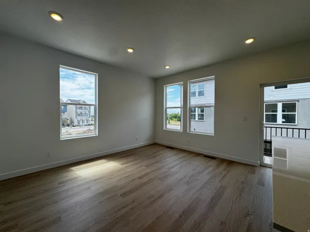 Spacious room featuring wood-finish flooring, recessed lighting, and multiple windows