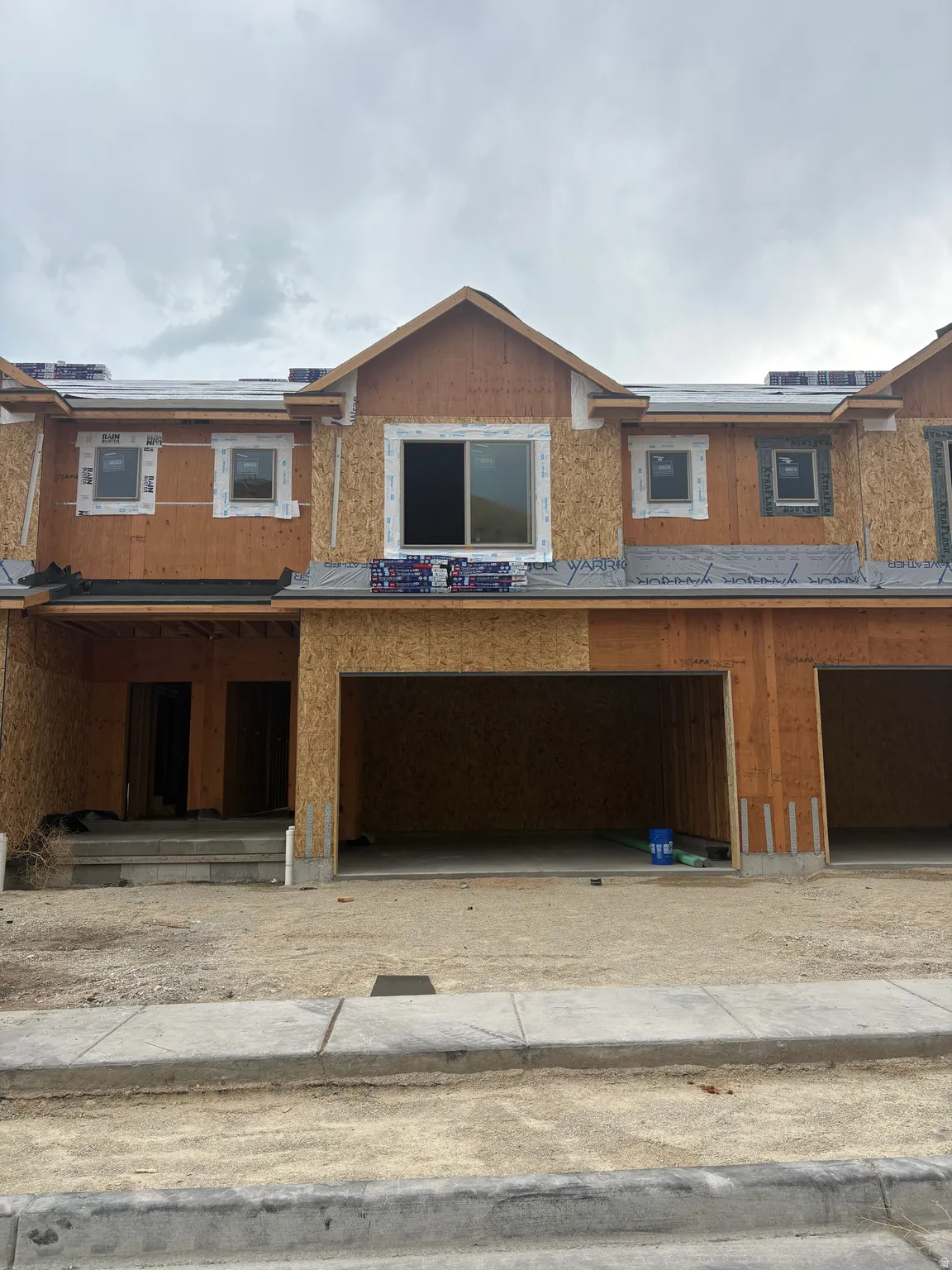 Exterior facade under construction featuring multiple windows, a prominent gable, and attached garage bays