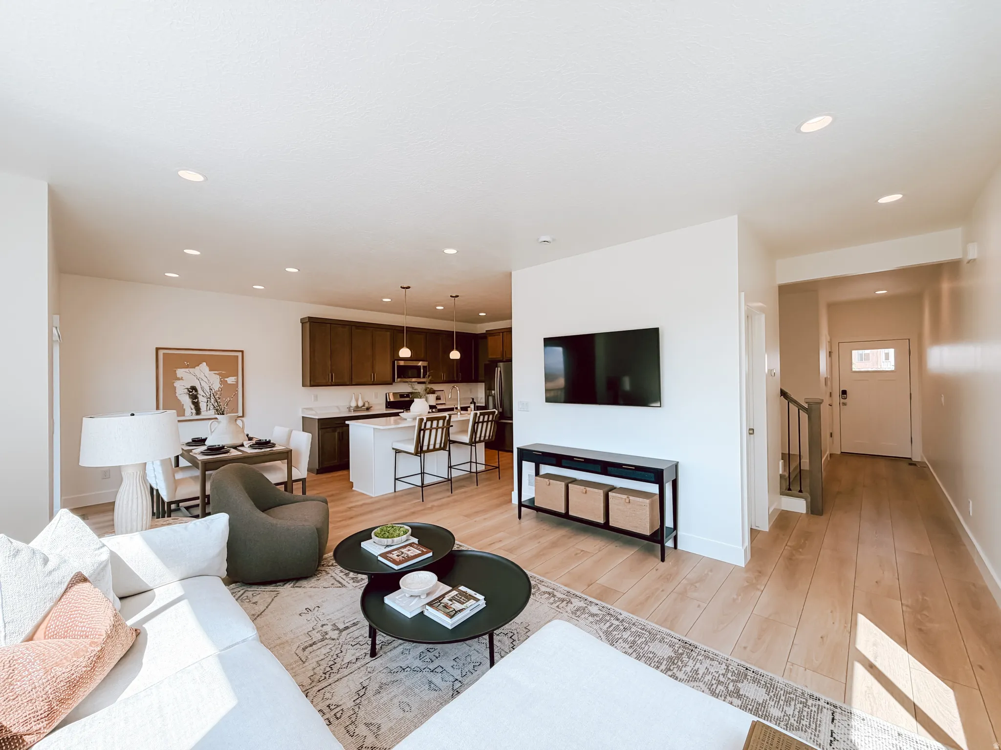 Open-concept living space featuring wood-finish flooring, recessed lighting, and a white interior color palette