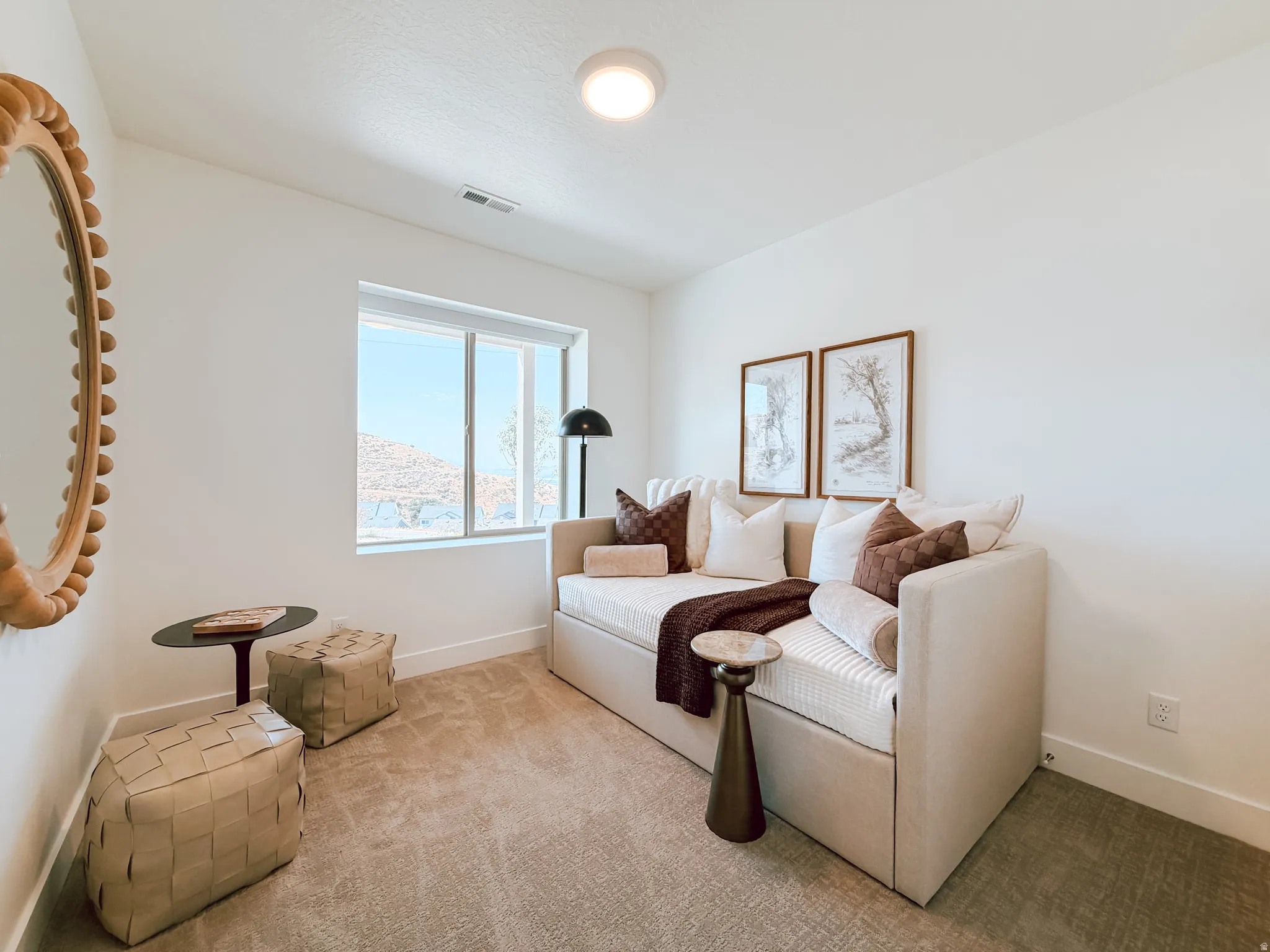 Bright room featuring a large window, neutral carpeting, and white walls with a contrasting baseboard