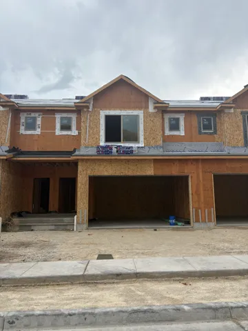 Exterior facade under construction featuring multiple windows, a prominent gable, and attached garage bays