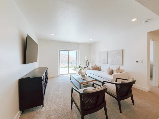 Living area featuring neutral-toned carpeting, recessed lighting, and a sliding glass door providing outdoor access