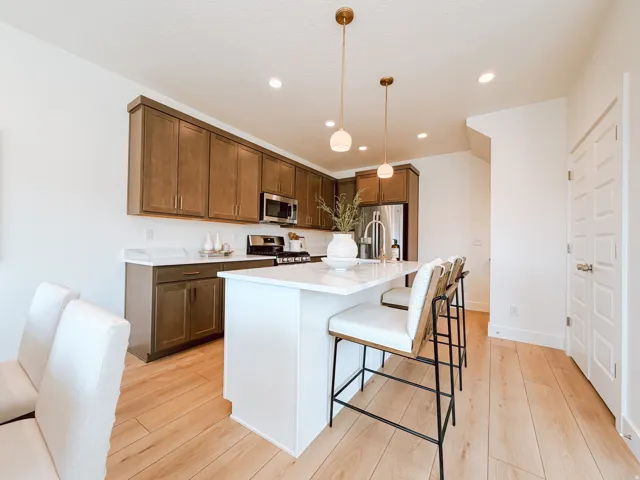 Kitchen featuring wood-finish flooring, white countertops, dark wood cabinetry, stainless steel appliances, and a central island with bar seating