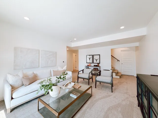 Open-concept living area featuring recessed lighting, light-toned carpeting, and a built-in architectural soffit
