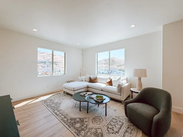 Bright living space with recessed lighting, large windows, wood-finish flooring, and white baseboards