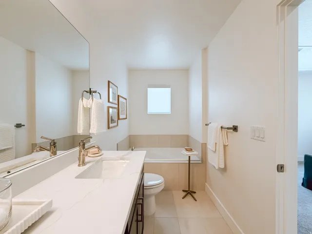 Contemporary bathroom featuring a large vanity with an integrated sink, polished chrome faucet, and expansive mirror